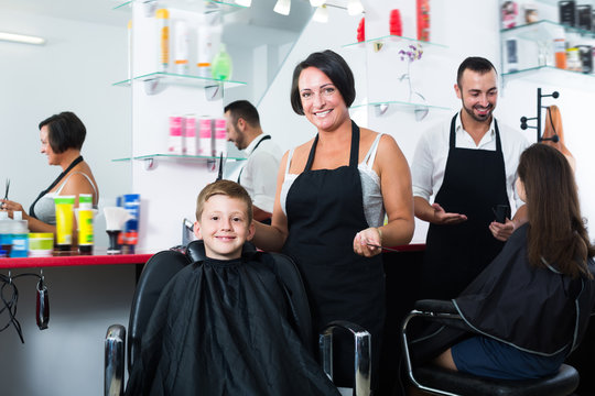 Kid getting hair cut by woman hairdresser