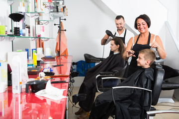Fototapeta na wymiar hairdresser cutting hair of boy in salon.