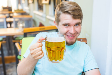 Man drinking beer. Handsome young man drinking beer while sitting at the bar outdoors