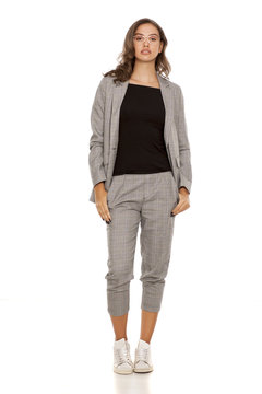 young beautiful woman in a jacket, blouse, sneakers, trousers and glasses