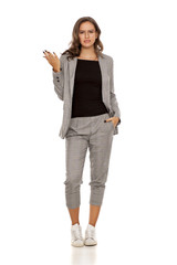 Nervous young beautiful woman in a jacket, blouse, sneakers, trousers and glasses