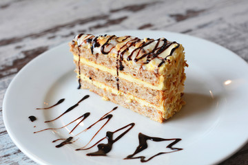 Sweets, cake, traditional hungarian,austrian cuisine. Esterhazy cake sliced on white plate close-up served with kumquat and almonds