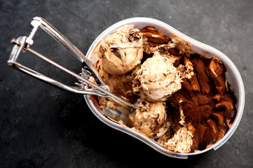 Ice cream with chocolate and caramel and a spoon for ice cream in a container