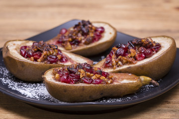 Homemade baked pears with honey, red cranberries and walnuts, close up