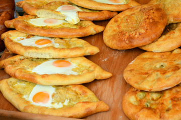 Adjarian khachapuri with eggs and kubdari on the wooden table. Khachapuri in Adjarian.