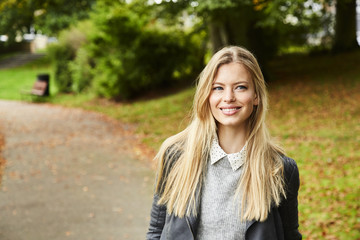 Smiling blond woman in park, looking away