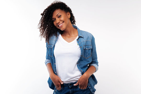 Charming Curly Woman Holding Hands In Pockets Of Jeans