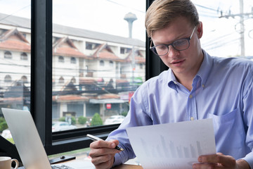 businessman use laptop with business plan document at workplace. man work with computer at office. finance market analyst analyze financial graph & chart diagram.