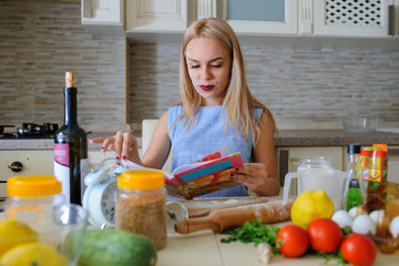 happy housewife reading cooking book in her kitchen