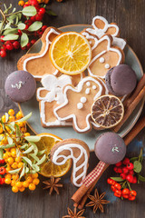 Merry christmas holiday decoration background with ginger man snowflakes snowman and tree cookies. Cinnamon, dry orange, cardamom, star, makarones. Dark wooden table.