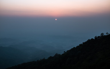Fototapeta premium Sunset scene on hight mountain. Sunshine through the clouds. silhouette at the mountain.
