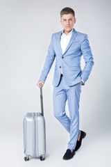young man in blue suit  with suitcase 