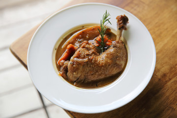 Coq au vin, chicken stewed in red wine with carrots and potatoes on wood background , France food