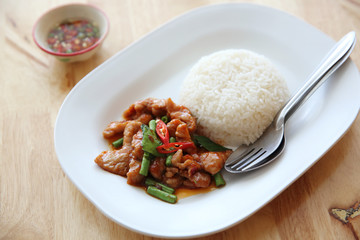 fried pork with thai curry and rice on wood background , Thai food