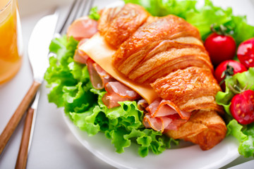 Fresh Croissant Sandwich with  Ham, Cheese,Cherry tomatoes and Salad leaf  on the Tray with  a glass of Juice Orange  Breakfast in bed Delicious Baking  Light Meal