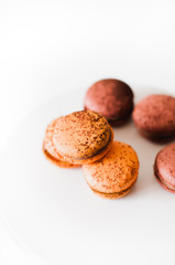 Close-up shot of passion fruit and espresso macarons, French meringue-based patissiere cookies filled with chocolate ganache abd dusted with cocoa powder on white background