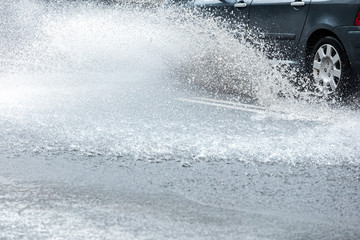 city road flooded with rainwater. splashing car on wet street.