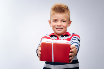 Fototapeta premium Cute little boy holding a red box with gift