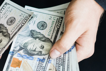 The white young man counts the money, one hundred new dollar bills on a black background close plan. Concepts of business and finance. top view .