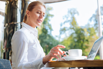 Pleasant businesswoman taking a cup of coffee