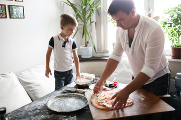 dad and son are preparing pizza in cozy kitchen