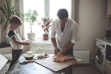 dad and son are preparing pizza in cozy kitchen