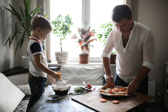 dad and son are preparing pizza in cozy kitchen