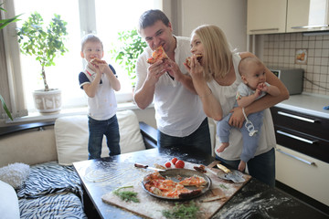 family with two children eating pizza at home