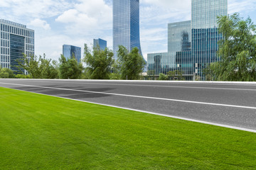 empty asphalt road and meadow front of modern buildings.