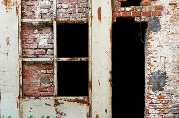 Muro antico di mattoni con porta arrugginita