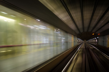 Metro subway of Turin (Italy), dark tunnel and train station with rails and motion blur seen from the running rain