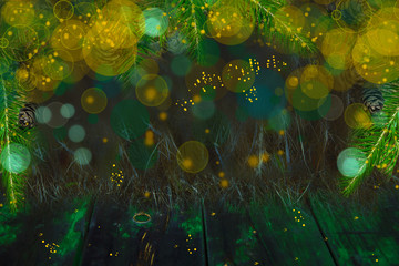 Fototapeta na wymiar Christmas and new year abstract background.Fir-tree branches on a dark wooden table with a yellow background blur, bokeh