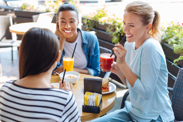Cheerful women listening to their friend during lunch