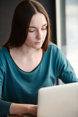 Young woman working on laptop while sitting at cafe