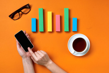 Hands working on orange desk  with colorful bar charts