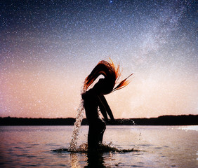woman on water background at night sky. Fantastic starry sky and the milky way