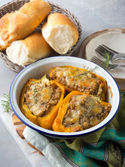 Bell peppers stuffed with barley and meat baked in enamel tin on gray