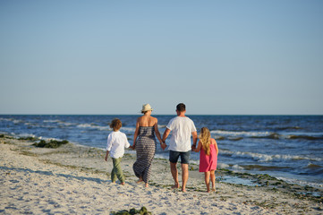 Happy family walks along the seaside holding hands.