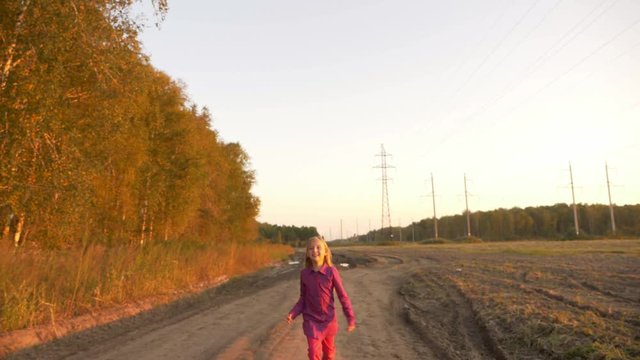 Happy young caucasian girl jumping by country road. White caucasian girl happy laughing.