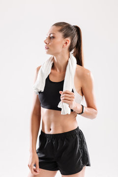 Slim young fitness woman with towel on her neck standing