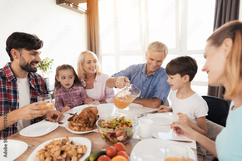 Wall mural The family gathered at the festive table for Thanksgiving. The old man spills a glass of juice