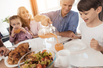 A man pours juice to his grandson, sitting at a festive table for Thanksgiving