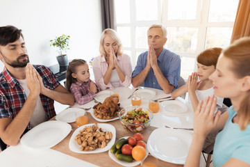 Family praying for a holiday table for Thanksgiving, holding folded hands in front of you