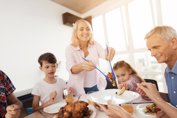 A middle-aged woman arranges food for her relatives. A little girl is pulling her hand to grab a cucumber