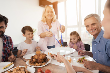 A woman is putting her salad in plates at the festive table for Thanksgiving Day
