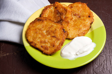 Potato pancakes with meat and sour cream on green plate in Belarusian style on dark background..
