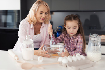 Obraz na płótnie Canvas Little girl with grandmother preparing a biscuit