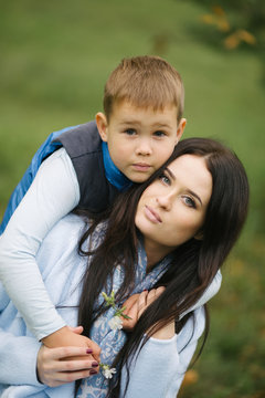 Portrait of a young and pretty woman and her son, a child in autumn clothes hugged Mom, a lady loves her child and treats him with tenderness and attention