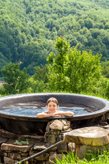 A boy is bathing in a large cast iron boiler in the mountains