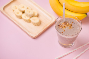 Fresh made banana smoothie in a glass on pink background